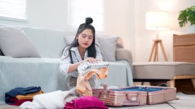 Asyalı bir kadın eşyalarını düzenliyor, onları bir seyahat çantasına koyuyor, bir tatil macerasına hazırlanıyor, yüksek kalite 4K görüntü.