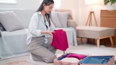Asyalı kadın eşyalarını dikkatlice seyahat çantasına koyar. Uzun bir hafta sonu için maceralı bir yolculuğa hazırdır. Yüksek kalite 4k görüntü