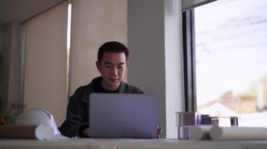 Genç Asyalı mühendis özenle dizüstü bilgisayarı üzerinde çalışıyor. Yüksek kalite 4k görüntü