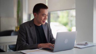 Genç Asyalı işadamı çalışma masasındaki bilgisayarında iş bilgisi yazıyor. - Evet. Yüksek kalite 4k görüntü