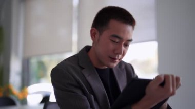 Genç Asyalı işadamı çalışma masasındaki tabletine iş verileri yazıyor. Yüksek kalite 4k görüntü