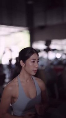Asyalı bir kadın, fitness meraklısı, koşu bandında koşu yaparak egzersiz yapmayı seviyor. Sağlıklı bir yaşam tarzını özveriyle kucaklamak. Yüksek kalite 4k görüntü