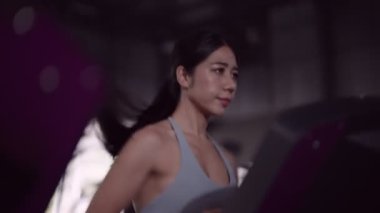 Asyalı bir kadın, fitness meraklısı, koşu bandında koşu yaparak egzersiz yapmayı seviyor. Sağlıklı bir yaşam tarzını özveriyle kucaklamak. Yüksek kalite 4k görüntü