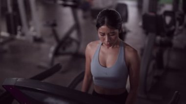 Asyalı bir kadın, fitness meraklısı, koşu bandında koşu yaparak egzersiz yapmayı seviyor. Sağlıklı bir yaşam tarzını özveriyle kucaklamak. Yüksek kalite 4k görüntü