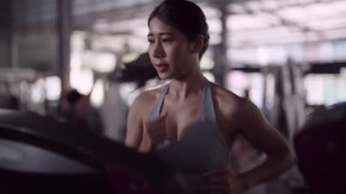 Asyalı bir kadın, fitness meraklısı, koşu bandında koşu yaparak egzersiz yapmayı seviyor. Sağlıklı bir yaşam tarzını özveriyle kucaklamak. Yüksek kalite 4k görüntü