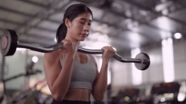 Asyalı kadın, sağlık meraklısı, dambıl kaldırarak kol kaslarını çalıştırıyor. Kendini fitness yolculuğuna adadı. Yüksek kalite 4k görüntü