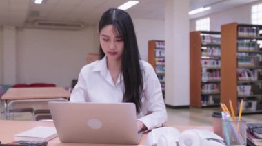 Genç Asyalı kız üniversite öğrencileri ödevlerini hararetle dizüstü bilgisayarlarında tamamlıyorlar, online iş veriyorlar, çevrimiçi derslere katılıyorlar. Yüksek kalite 4k görüntü