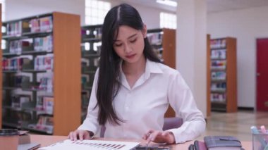 Genç Asyalı bayan üniversite öğrencileri çeşitli istatistiksel değerleri hesaplamak için matematik ödevleri üzerinde özenle çalışıyorlar. Yüksek kalite 4k görüntü