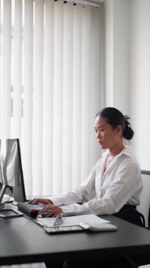 Ofisinde çalışan Asyalı iş kadını bilgisayarında yazı yazıyor. Mesleki hayatı kucaklayarak, ofis alanındaki görevlerini verimli bir şekilde tamamlıyor. Yüksek kalite 4k görüntü