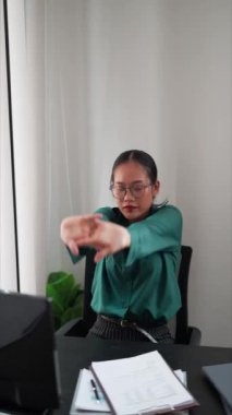 Asyalı iş kadını, iş yerinde esneyerek ve vücut egzersizleri yaparak işten kaytarıyor. Yüksek kalite 4k görüntü