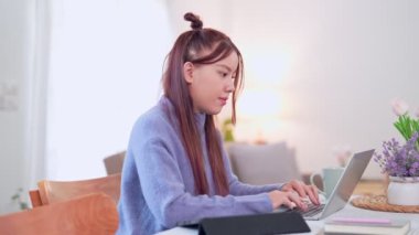 Evde çalışan Asyalı iş kadını oturma odasındaki masada dizüstü bilgisayarını kullanıyor. - Evet. Yüksek kalite 4k görüntü