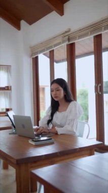 Asyalı genç bir iş kadını, yakınlardaki bir kafede laptopunu odaklanma ve kararlılıkla kullanıyor. - Evet. Yüksek kalite 4k görüntü
