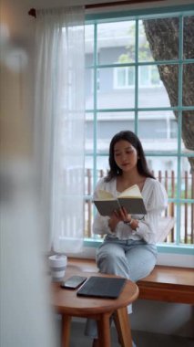 Yakın bir kafede çalışan Asyalı bir bayan girişimci, işle ilgili kitapları okumaya dalmış, ofis dışında odaklanmış ve çalışkan bir uzaktan çalışma sergiliyor. Yüksek kalite 4k görüntü