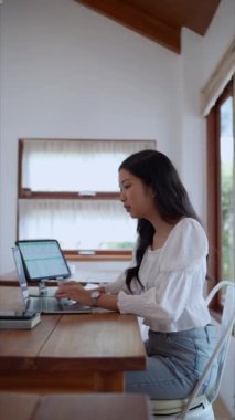 Asyalı genç bir iş kadını, yakınlardaki bir kafede laptopunu odaklanma ve kararlılıkla kullanıyor. - Evet. Yüksek kalite 4k görüntü