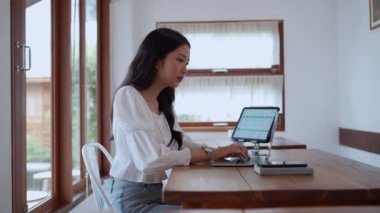 Asyalı genç bir iş kadını, yakınlardaki bir kafede laptopunu odaklanma ve kararlılıkla kullanıyor. - Evet. Yüksek kalite 4k görüntü