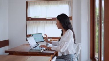 Asyalı genç bir iş kadını, yakınlardaki bir kafede laptopunu odaklanma ve kararlılıkla kullanıyor. - Evet. Yüksek kalite 4k görüntü