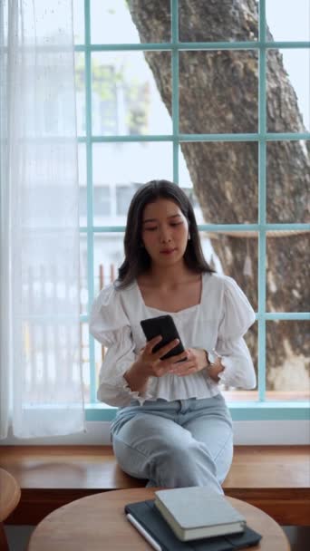 近くのカフェで働くアジアの女性起業家は スマートフォンで集中的で勤勉なビデオ通話に従事し オフィスの外でリモートワークを披露しました 高品質のフルHd映像 — ストック動画