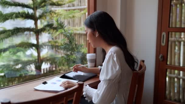 Azjatka Przedsiębiorczyni Pracująca Pobliskiej Kawiarni Pilnie Notuje Swoje Zadania Pomocą — Wideo stockowe