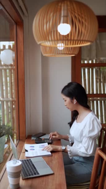近くのカフェで働くアジアの女性起業家は 電卓を使って今後の四半期費用を予算に充て 集中したリモートワークを実証しました 高品質の4K映像 — ストック動画