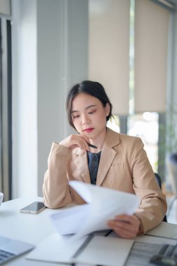 İş kadınları, kağıt üzerinde notlar alırken ve dijital dizüstü bilgisayar üzerinde teknolojiyle çalışırken, yeni başlatılan proje hakkında analiz stratejisi yatırımı ve yönetimi için iş belgesi okuyorlar.
