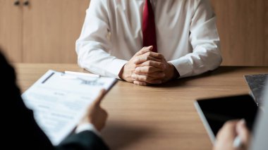 İş görüşmesi sırasında erkek adayla özgeçmiş okuyan ve tablete veri yazan İK yöneticisi kadın.