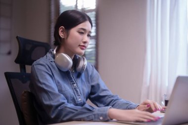 Online derste derslere hazırlanan Asyalı genç kadın öğrenciler dizüstü bilgisayarla ders çalışıyor ve ev ödevi yaparken veri yazma ve evden bilgi uzaktan eğitimi alma konusunda eğitici olduğunu düşünüyorlar..