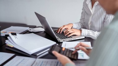 İki iş yeri gayrimenkul satıcısı, emlak yatırımlarını hesaplamak ve tartışmak için hesap makinesi kullanırken, aynı zamanda ev satış sözleşmesi ve ofis bilgisayarında ev sigortası hakkında terimler yazıyorlar..