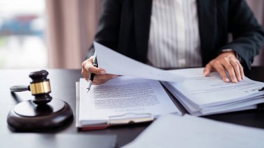 Avukat iş kadını elinde dava açma belgesi tutarken ve mali iş verilerini incelerken, yasa anlaşması ve hukuk firmasındaki iş sözleşmesi verilerinin analizi de yapılıyor..