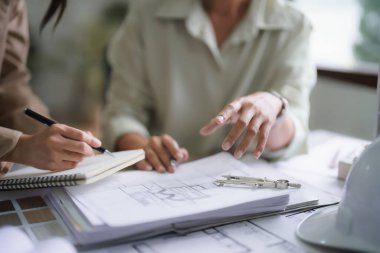 İki kadın mimar, iç mimarlık projesini planlar ve notlar üzerine tartışıyor..