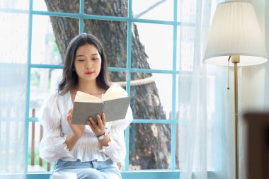 Genç Asyalı iş kadını edebiyat okumaktan zevk alıyor. Kitap ve rahatlama, analiz sonrası kahve içme stratejisi üzerine yatırım ve kafede yeni bir başlangıç projesi planlama üzerine..