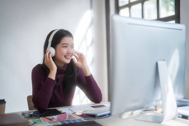 Grafik tasarımcı serbest kadınlar, müzik dinlemek için kulaklık takıyor logo markası çizdikten sonra rahatlıyor ve ev stüdyosunda teknolojik ekipmanlarla grafik tasarımı tasarlamaya çalışıyorlar..