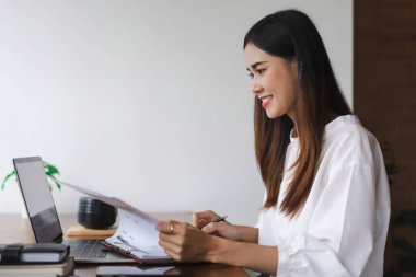 İş kadınları ofis dışında çalışırken dizüstü bilgisayarda veri okuyorlar ve finans belgelerini kontrol ediyorlar.