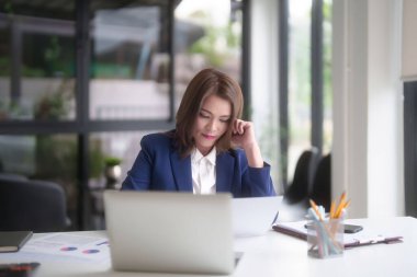 Asyalı iş kadınları pazarlama iş raporlarını okurken ve finans tablosunu kontrol ederken yeni iş stratejisi hakkında düşünürken aynı zamanda ofis dışında yeni bir girişimin yatırım ve pazar stoklarını analiz ediyorlar..