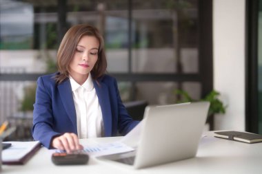 Pazarlama ticaret belgesini okuyan ve hesap makinesi kullanan Asyalı iş kadınları, ofis dışındaki yeni girişimin yatırım ve pazar stoklarını analiz ederken, finans tablosunu kontrol etmek için istatistikleri hesaplarlar..