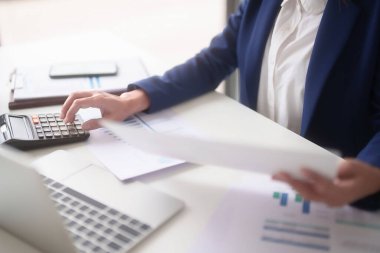 Pazarlama ticaret belgesini okuyan ve hesap makinesi kullanan Asyalı iş kadınları, ofis dışındaki yeni girişimin yatırım ve pazar stoklarını analiz ederken, finans tablosunu kontrol etmek için istatistikleri hesaplarlar..