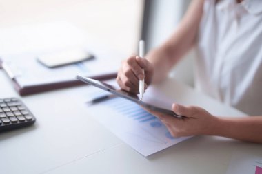 Asyalı iş kadınları dijital tablet ve yeni iş dünyasının finans belgesini okurken, aynı zamanda ofis dışındaki yeni girişimin yatırım ve pazar stoklarını analiz ederler..