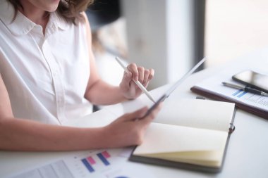 Asyalı iş kadınları dijital tablet ve yeni iş dünyasının finans belgesini okurken, aynı zamanda ofis dışındaki yeni girişimin yatırım ve pazar stoklarını analiz ederler..