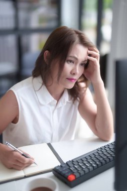 Bilgisayarla ilgili pazarlama raporlarını okuyan Asyalı iş kadınları, yeni iş piyasalarının pazarlamasını planlamak ve yeni girişimlerin yatırım ve pazar stoklarını analiz ederken not defterlerine not almak hakkında düşündüler..