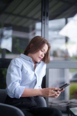 Asyalı iş kadınları ticari bilgileri araştırmak ve pazarlama raporlarını okumak için akıllı telefonu kullanırken, aynı zamanda iş yerinin dışındaki yeni girişimlerin yatırım ve pazar stoklarını analiz etmeye çalışıyorlar..