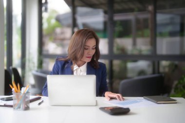 Pazarlama sektörü raporunu okuyan Asyalı iş kadınları, ofis dışındaki yeni girişimin yatırım ve pazar stoklarını analiz ederken, finansal harita verilerini kontrol etmeye ve klavye bilgisayarında veri yazmaya başladılar..