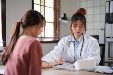 Kadın hastaların kan basıncını ve kalp atışlarını ölçmek için dijital sphygmomanometre kullanan Asyalı psikolog kadınlar klinikte tedavi ve ruhsal sağlık tedavisi hakkında danışmanlık yaparken,.