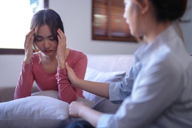 Asyalı psikolog kadınlar hastaları teşvik etmek ve ilaç ve ruh sağlığı terapisi hakkında danışmanlık yaparken, kadın hastalar psikolojik sağlık sorunları ve baş ağrıları hakkında.