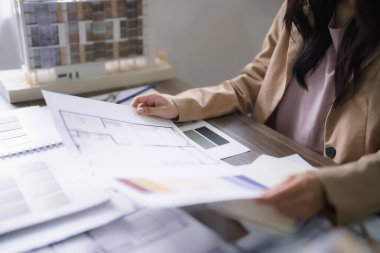 İç yapı projesinin çizimini ve plan üzerindeki renk örneklerini kontrol eden kadın mimar.