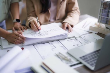 İki kadın mimar iç mimari hakkında tartışıyorlar. İnşaat projesi tasarlıyorlar ve plan üzerinde çizim yapıyorlar..