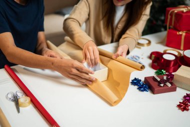 Genç bir adam ve kadın mutlu bir şekilde masayı dolduruyor, birlikte eğlenceli bir anı paylaşıyorlar. Etrafları Noel süsleriyle çevrili ve bir Noel ağacı festival atmosferine katılıyor..