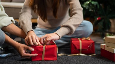 Genç bir çift yerde oturuyor, Noel hediyelerini paketliyorlar. Sahne şenlikli dekorasyonlar ve hediyelerle dolu. Sıcak bir tatil ortamı yaratıyor..