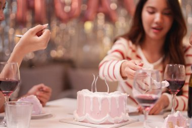 Kutlamanın keyfini çıkaran neşeli bir arkadaş grubu şenlikli bir ortamda pasta ve şarapla birlikte. Atmosfer canlı, dostluğu ve birlikteliği vurguluyor..