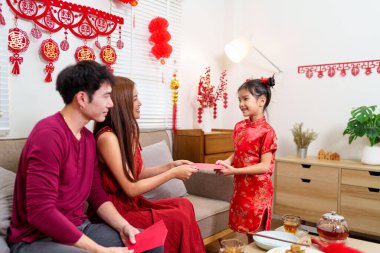 Bir çocuk Çin 'deki yeni yıl kutlamaları sırasında ebeveynlerinden sevinçle kırmızı bir zarf (angpao) alır..