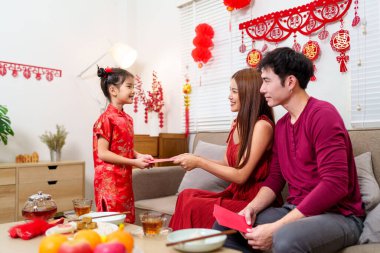 Bir çocuk Çin 'deki yeni yıl kutlamaları sırasında ebeveynlerinden sevinçle kırmızı bir zarf (angpao) alır..