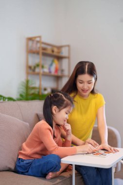  Bir anne ve kızı, bir masada birlikte oynaşarak eğleniyor, kahkahaları ve bağlantıları paylaşıyor..